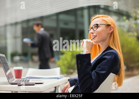 Geschäftsfrau, die Arbeiten am Tisch außerhalb Bürogebäude Stockfoto