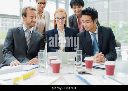 Business-Leute versammelten sich um Laptop in Bürogebäude Stockfoto