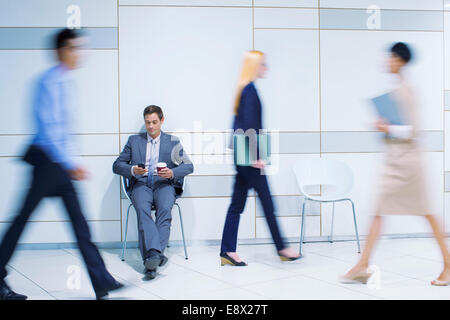 Geschäftsmann, sitzen mit Handy im Bürogebäude Stockfoto