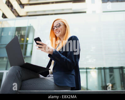 Geschäftsfrau, die sitzen auf Bank mit Handy Stockfoto