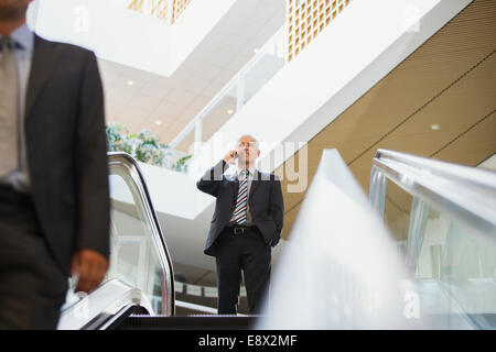 Geschäftsmann am oberen Ende der Treppe im Bürogebäude am Handy sprechen Stockfoto