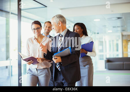 Geschäftsleute gehen und sprechen im Büro Stockfoto
