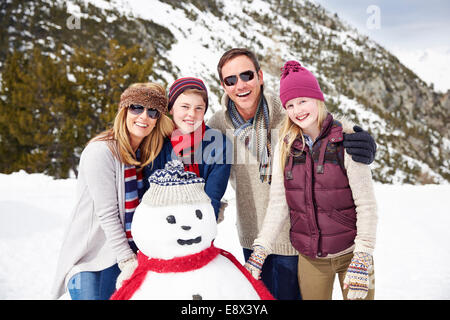 Familie gemeinsam einen Schneemann bauen Stockfoto