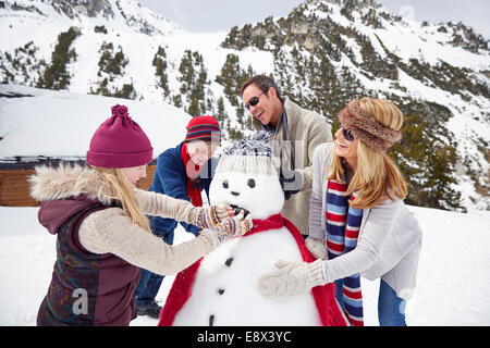 Familie gemeinsam einen Schneemann bauen Stockfoto