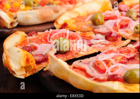 Pizza mit Salami, Peppeeoni, Oliven, Tomaten und gelbe Paprika Stockfoto