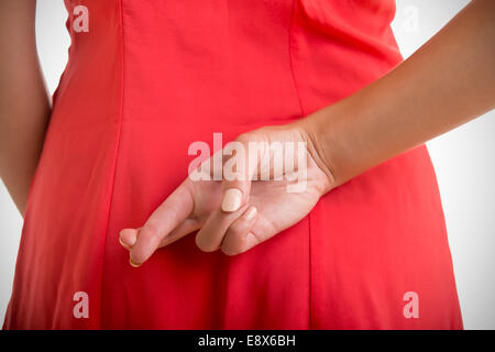 Nahaufnahme von gekreuzten Fingern hinter einer Frau Rücken Stockfoto