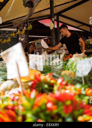 Mann-Betrieb bis zu einem Obst und Gemüse Stand am Markt von Rialto in Venedig, Italien. Bunte Chili im Vordergrund. Stockfoto