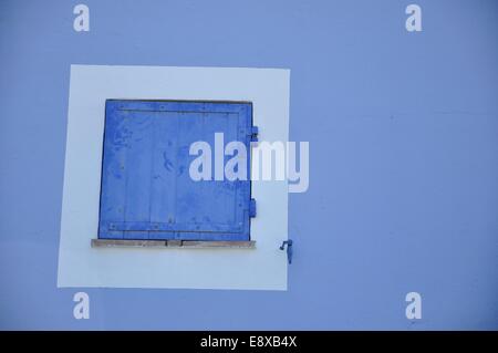 eine staubige blau shutter mit Fingerabdrücken, mit einer weißen Einfassung auf einer blauen Wand in Port Grimaud, Provence, Frankreich Stockfoto