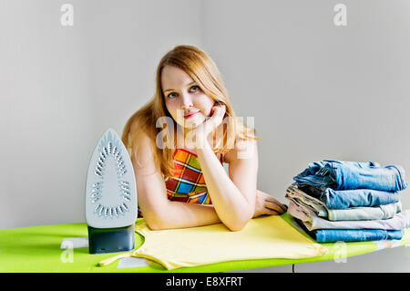 Glückliche junge schöne Frau Kleidung bügeln. Hausarbeit Stockfoto