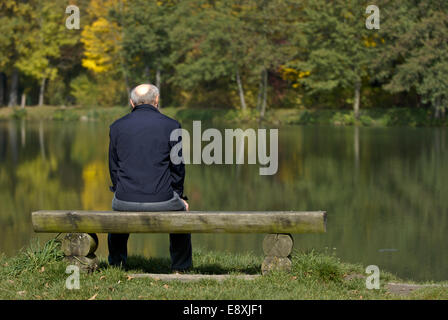 Älterer Mann sitzt auf einer Bank Stockfoto