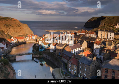 Sonnigen abend Blick auf die malerisch sonnendurchflutete Seaside Cottages, hohen Klippen & Hafen der alten Fischerdorf - Staithes, North Yorkshire, England, UK. Stockfoto