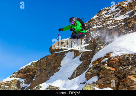 Frau Skifahrer Sprung von einer Klippe in den Bergen an einem sonnigen Tag Stockfoto