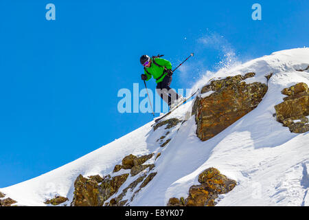 Frau Skifahrer springen über eine Klippe gegen den blauen Himmel in den Bergen an einem sonnigen Tag Stockfoto