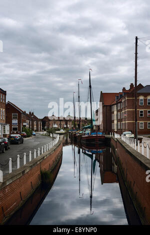 Alte, Vintage, Lastkähne verankert entlang des Ufers des Beck bei Beverley mit Häusern und Wohnungen in Beverley, Yorkshire, Großbritannien. Stockfoto