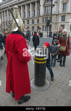 Kind Grimassen an ein Mitglied der Household Cavalry, Life Guards Regiment, Wache außerhalb der Horse Guards Parade, London, England Stockfoto