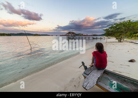 Touristischen beobachten einen entspannenden Sonnenuntergang sitzen am Strand, Togean Islands, Zentral-Sulawesi, Indonesien. Stockfoto