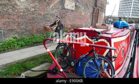 London UK. 16. Oktober 2014. An einem warmen Herbstnachmittag Zyklen eine ältere Frau im Herbst vorbei Regents Canal Boote in der Nähe von Kings Cross. KATHY DEWITT/Alamy Live-Nachrichten Stockfoto