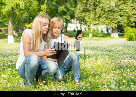 Junge und ein Mädchen mit einem digitalen Tablet und Smartphone Stockfoto