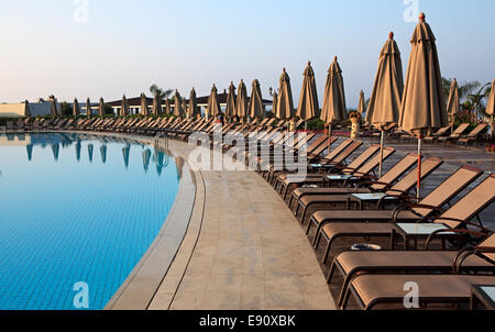 Chaiselongue und Sonnenschirme am Pool. Stockfoto