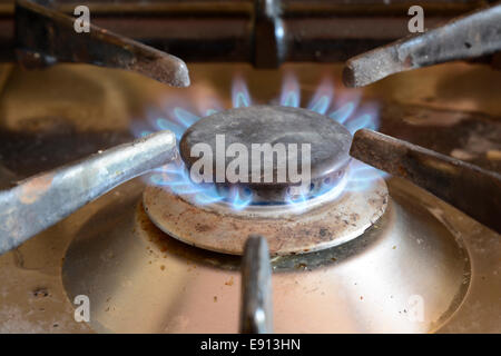 Blaue Flamme auf einem inländischen Gas-Herd-Ring. Schmutzig mit Essen spritzt. Stockfoto