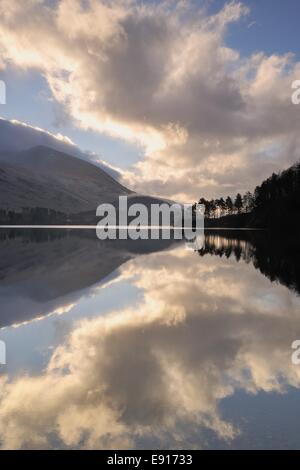 Kurz nach Sonnenaufgang zündete es Wolken durch die tief stehender Sonne zu reflektieren, in das Stille Wasser eines Sees in der Nähe von Keswick im Lake District. Stockfoto