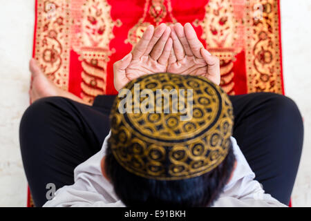 Asiatische muslimischen Mann, der betet auf Teppich tragen traditionelle Kleidung Stockfoto