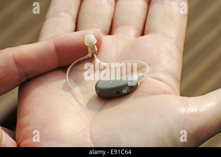 Moderne kleine Hörgerät in die Hand einer Frau Stockfoto