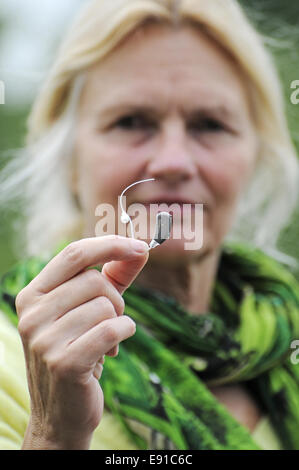 Moderne kleine Hörgerät in die Hand einer Frau Stockfoto