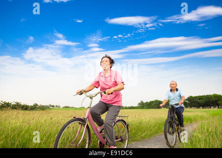 Glücklich asiatischen ältere Senioren paar Biken im Bauernhof mit blauem Himmelshintergrund
