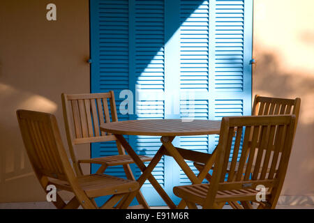 Colònia de Sant Pere, Mallorca, Balearen, Spanien. Tisch und Stühle auf Balkon des modernen Wohnung, blauen Fensterläden über. Stockfoto