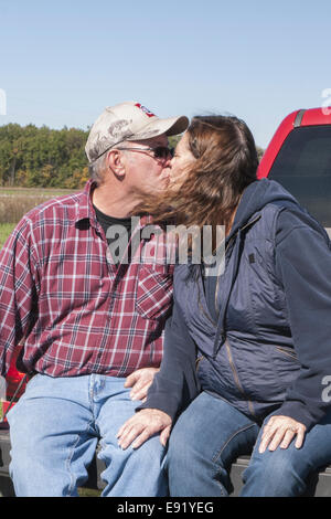 Reifer Mann und Frau sitzen auf Heckklappe LKW zu küssen Stockfoto