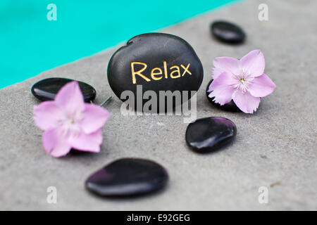 Stein mit dem Wort Relax und Blumen Stockfoto