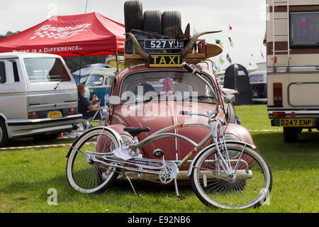 Ratte-VW-Käfer auf einem Campingplatz mit einem Low rider Fahrrad und Ersatzreifen Stockfoto