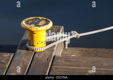 Gelbe Festmacher Poller mit nautischen Seil auf hölzerne pier Stockfoto