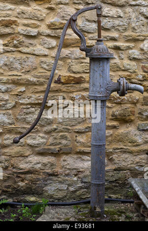 Old Fashioned Wasserpumpe neben einer Steinmauer Stockfoto