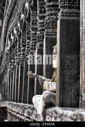 Porträt von älterer Mann sitzt vor der Haustür von einem hölzernen Hindu Tempel in Kathmandu, Nepal. Stockfoto