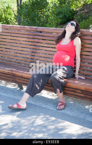 Schwangere Frau müde sitzen auf einer Bank ausruhen Stockfoto