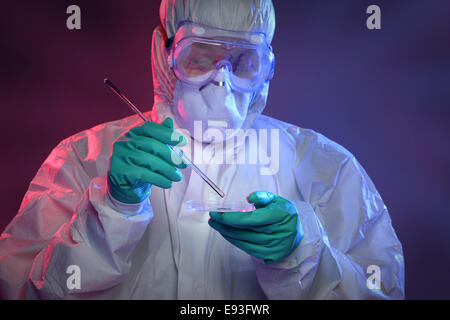 Wissenschaftler im Schutzanzug und schützendes Zahnrad auf Petrischale mit Viren arbeiten Stockfoto