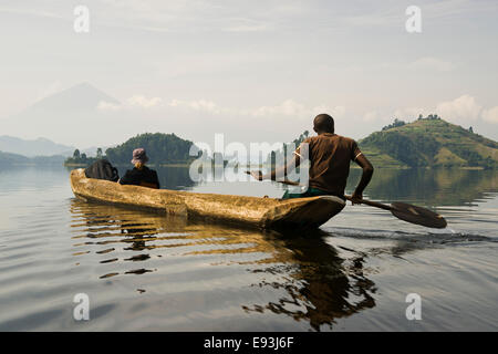 Führer und Frau im Kanu am Morgen Nebel Mutanda See vor Muhavura Vulkan an der Grenze zu Ruanda, Kisoro, Uganda Stockfoto