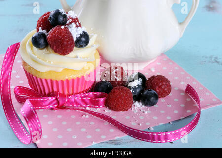 Leckere Cupcake mit Beeren und Vintage Sugar Bowl auf Retro-Aquablau shabby chic Tisch Stockfoto