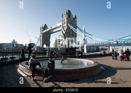 "Mädchen mit einem Delfin" entstand 1973 durch Künstler David Wynne. Tower Bridge im Hintergrund. Befindet sich am nördlichen Ufer der Themse in der Nähe von Tower Bridge. Die Statue sitzt direkt am Wasser vor dem Tower Hotel. Die Statue ist bekannt für seine Darstellung von Bewegung, so dass die Illusion der Figuren fliegen nicht unterstützt. Stein Stockfoto