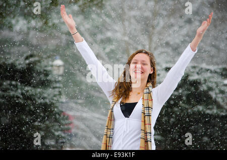 Leise rieselt der Schnee: eine junge Frau wirft ihre Arme Sieg einer schönen Schnee-Dusche. Stockfoto