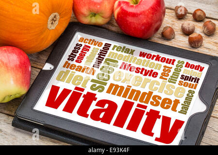 Vitalität und Lebensenergie Wortwolke auf digitale Tablett mit Äpfel, Kürbis und Haselnüssen Stockfoto