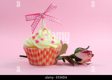 Hübsche rosa Cupcake mit blass rosa Seide rose Knospe auf rosa Hintergrund für weibliche Geburtstag, Hochzeit, Valentinstag oder Muttertag. Stockfoto