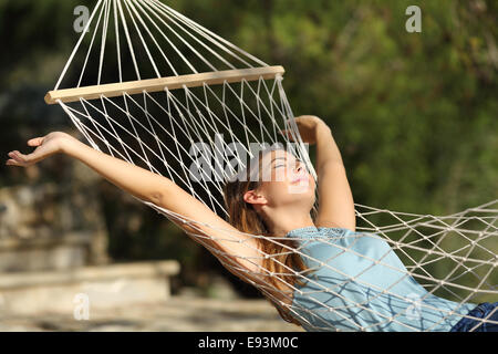Glückliche Frau entspannt in einer Hängematte auf Urlaub und Arme in den Bergen Stockfoto