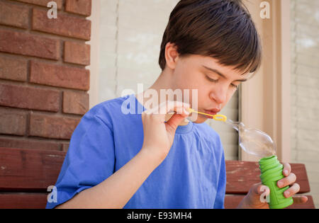 Hübsches Kind mit Autismus und Down-syndrom Seifenblasen Stockfoto