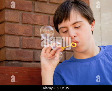 Junge mit Autismus und Down-syndrom Seifenblasen außerhalb Stockfoto