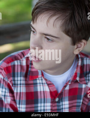 Teenager mit Autismus und Down-Syndrom in rot, kariert, Hemd Stockfoto