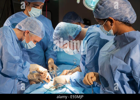 Ein Team von interracial Ärzte männlichen & weiblichen Chirurgen in der Chirurgie bei einem Patienten mit verschiedenen medizinischen Geräten in Betrieb Stockfoto