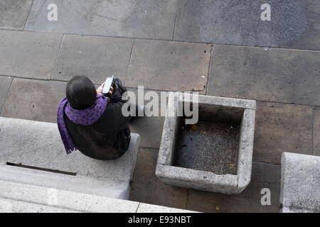 Luftaufnahme von eine Dame auf einer Bank mit einem Mobiltelefon in der hand Stockfoto
